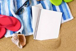 Certains éléments sur une serviette de plage, cahier tong et lunette de soleil